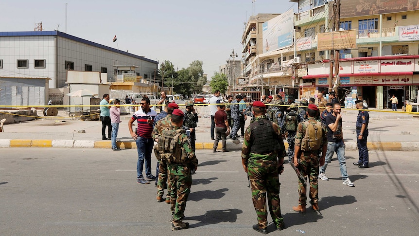 Iraqi security forces gather at the site of a bomb blast.