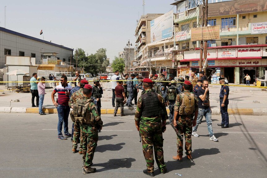 Iraqi security forces gather at the site of a bomb blast.