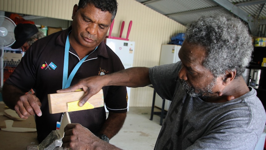 Two Indigenous men in workshop working with wood