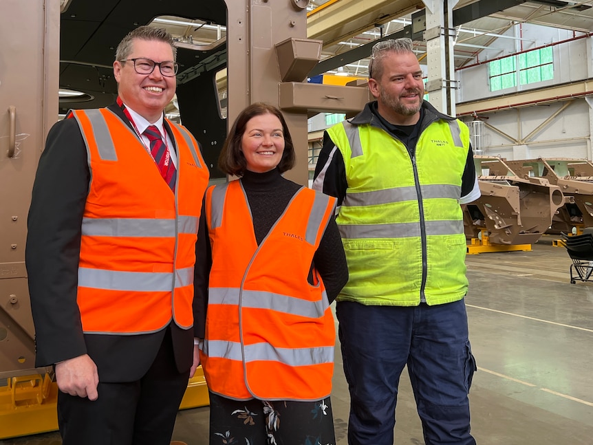a photo of politicians and workers in hi vis in a factory 