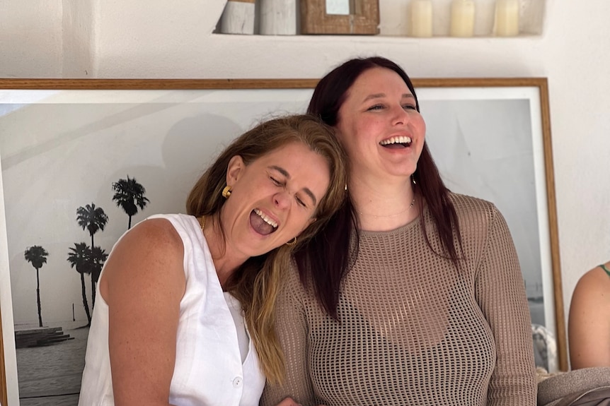 Two women sitting next to each other and laughing.