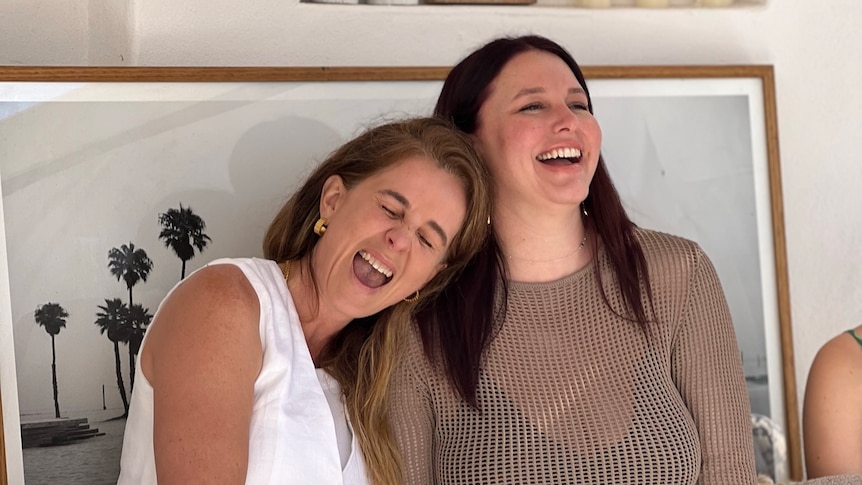 Two women sitting next to each other and laughing.