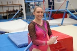 Gymnast Emliy Little brushes chalk on her hands in a gym in Perth.