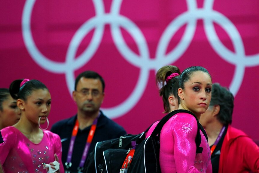 Larry Nassar stands behind members of the US gymnastics team.