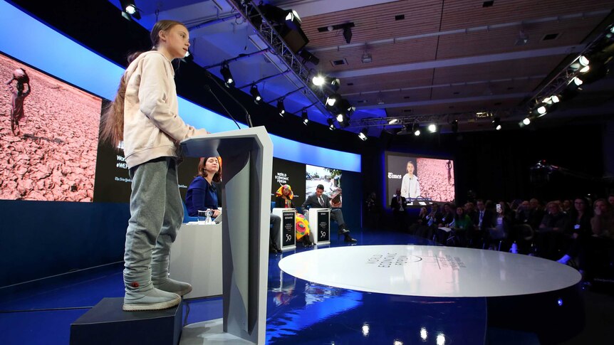 A young woman stands on a podium speaking to an audience