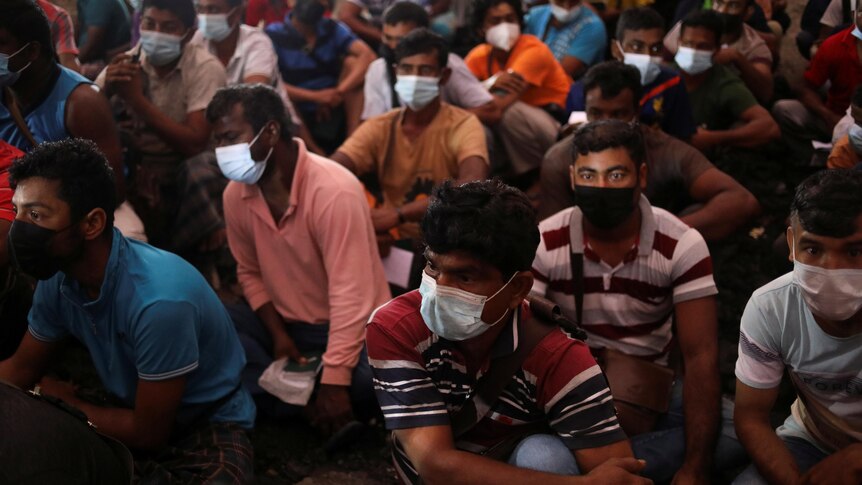 A group of people sit cramped together wearing face masks in Malaysia.