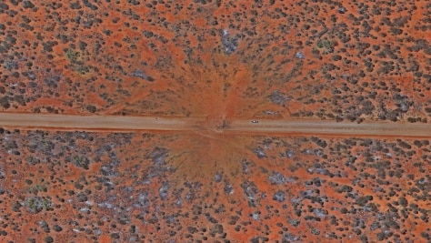 An aerial shot showing the crater left by a huge explosion in the desert.