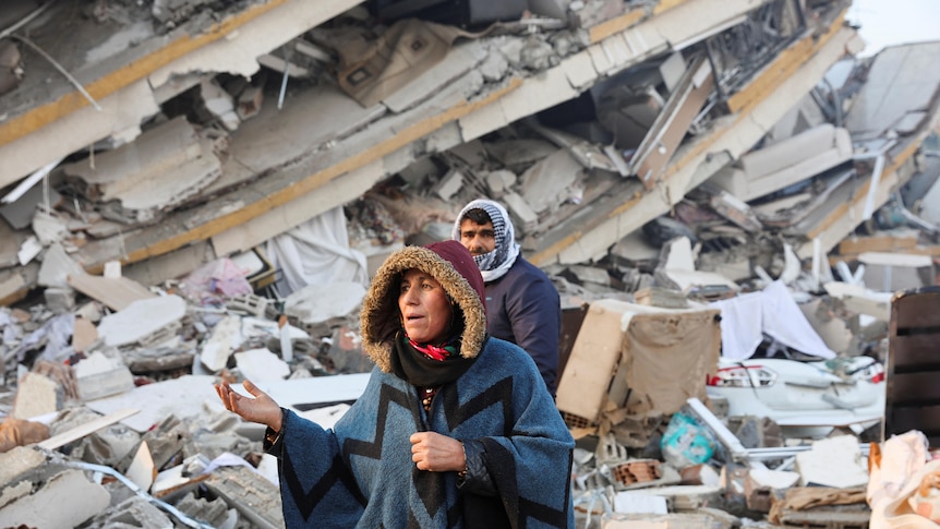 A woman gestures in front of a building 