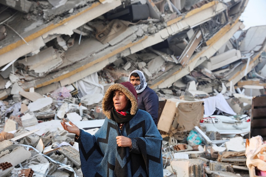 A woman gestures in front of a building 