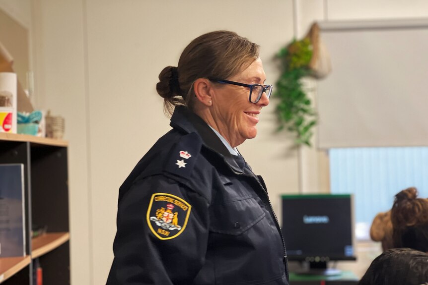 A woman with glasses wears a prison manager uniform. 