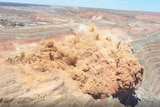 An aerial view of an explosive blast at an open pit gold mine.