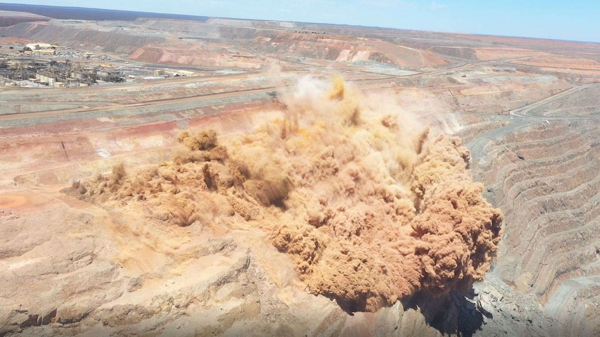 An aerial view of an explosive blast at an open pit gold mine.