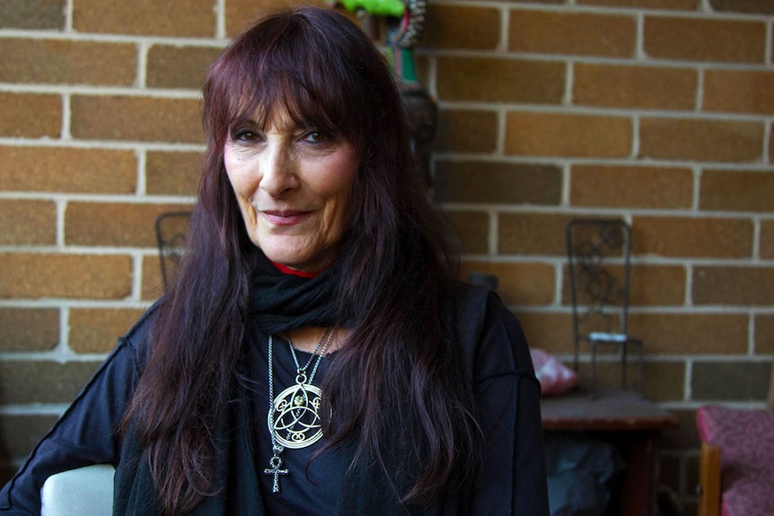 Coven leader Leonora Jackson sitting in front of brick wall.