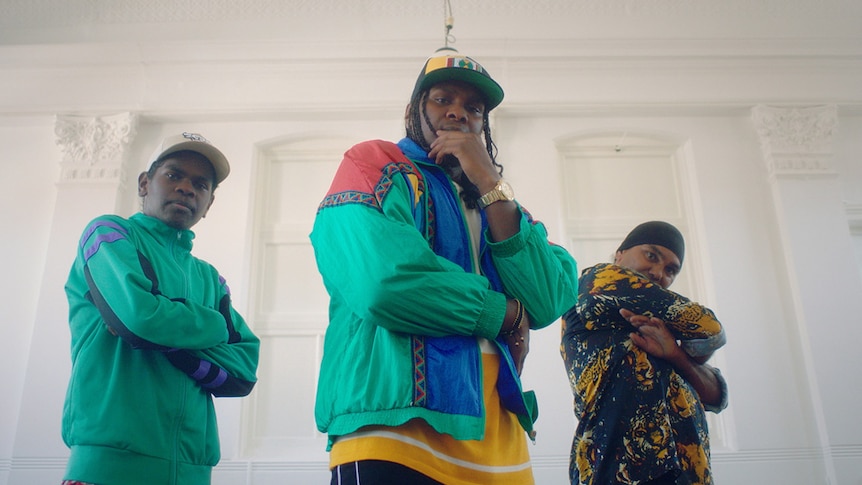 A still from Baker Boy's 2019 music video for Cool As Hell of him posing alongside two dancers