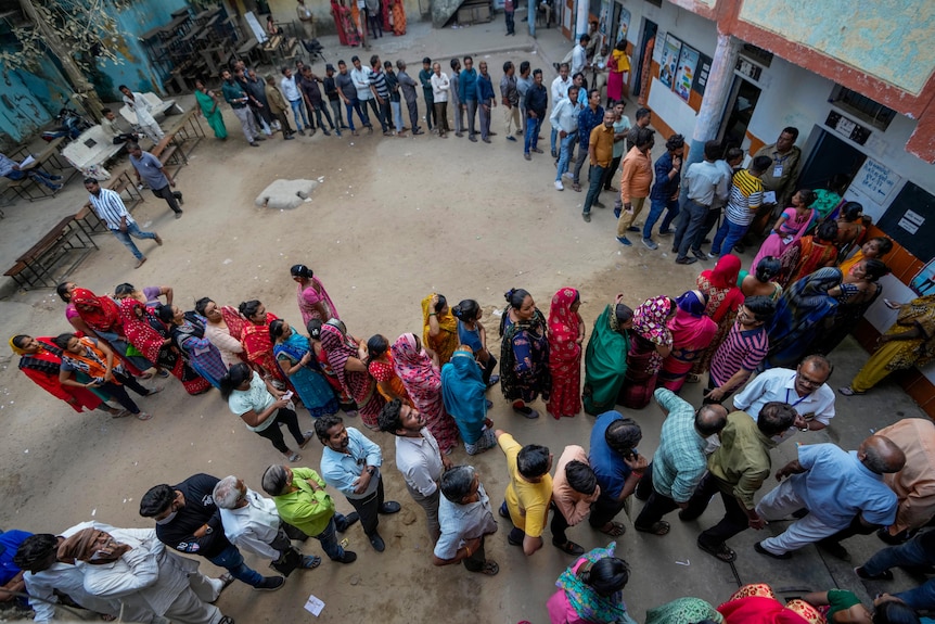 People stand in queue to cast their votes during the second phase of Gujarat state legislature elections in Ahmedabad, India.