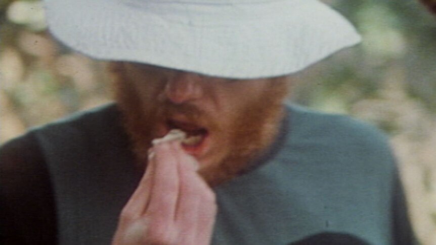 Greg Mead is pictured "gnawing" into a goanna that was killed and cooked by the group.