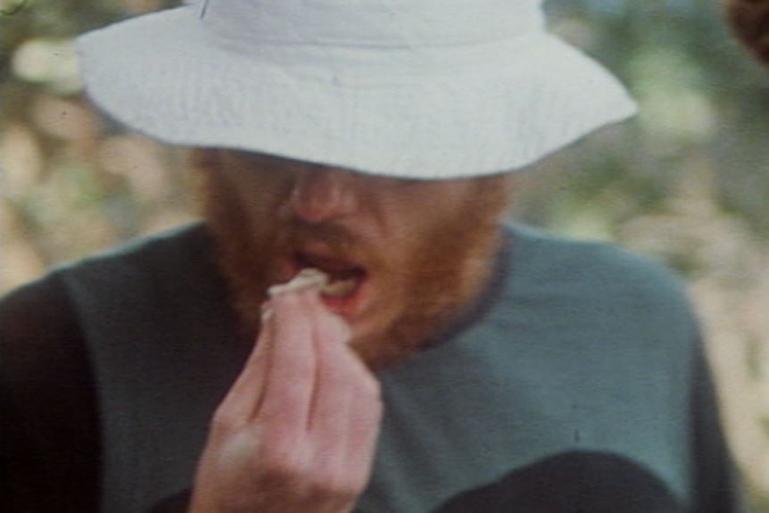 Greg Mead is pictured "gnawing" into a goanna that was killed and cooked by the group.