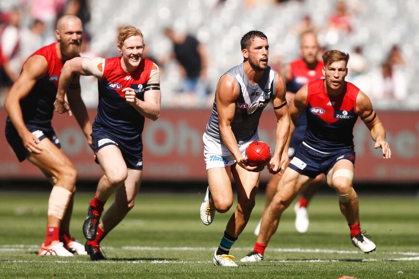 Port Adelaide's Travis Boak looks to handpass the ball under pressure against Melbourne