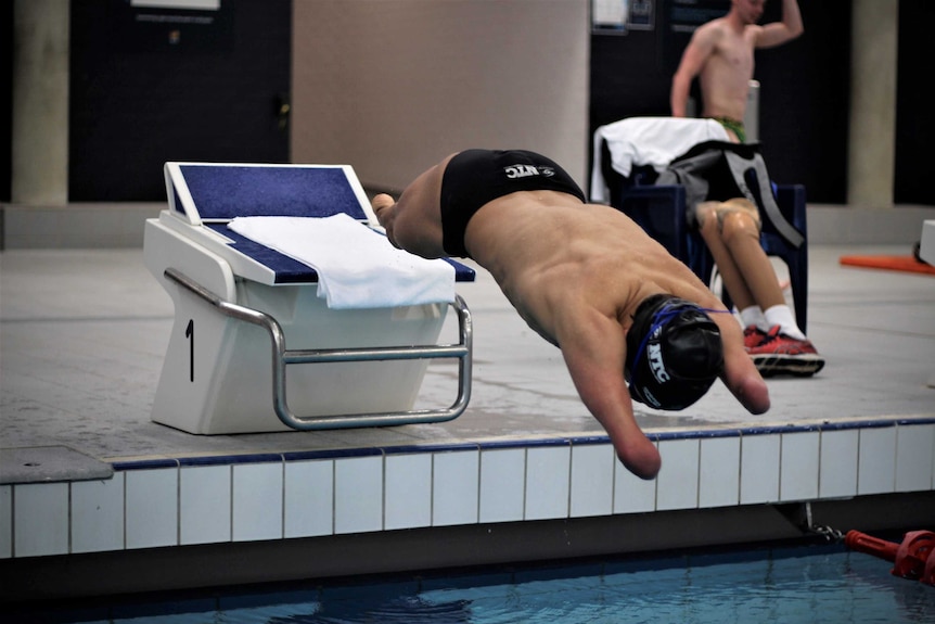 Ahmed Kelly dives off a platform into the pool during a training session.