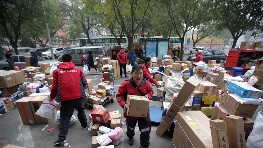 Deliverymen wearing red work among parcels beside a road in Beijing, China.