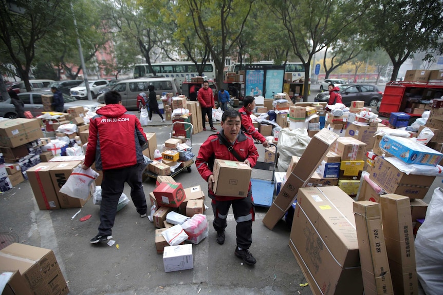 Deliverymen wearing red work among parcels beside a road in Beijing, China.