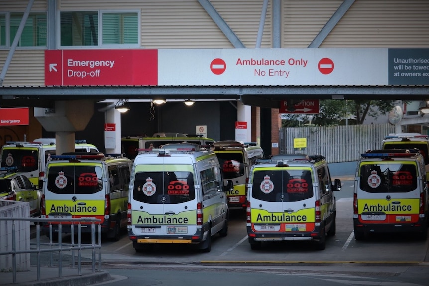 Eight ambulances at parked at a lower lavel entrance to the hospital. 