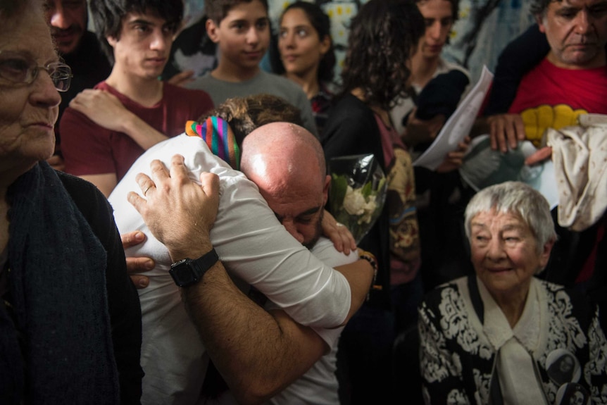A bald man embraces a relative during a press conference about the discovery of Argentina's missing grandchild 121.