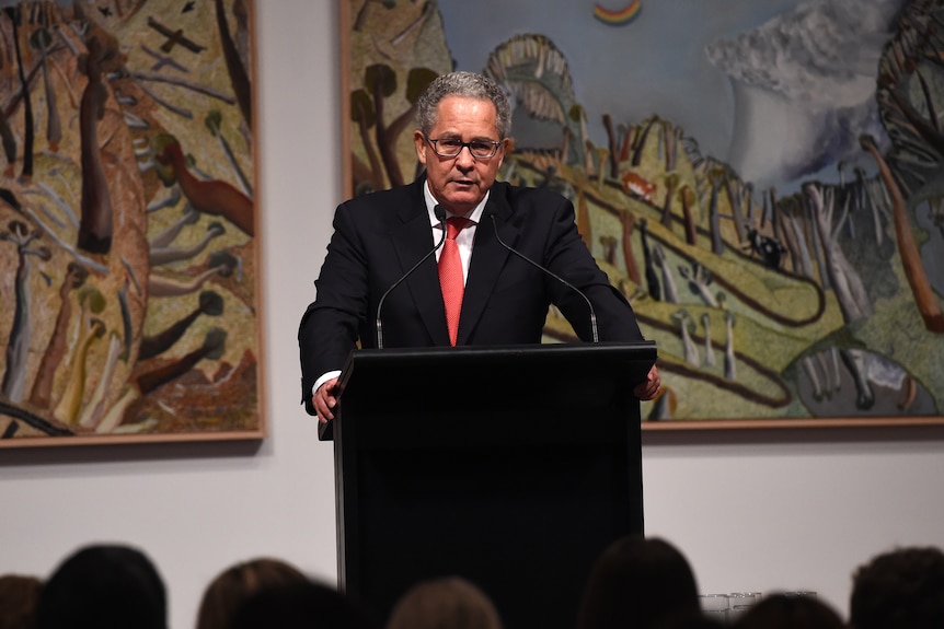 Peter Carne speaks in front of a microphone.