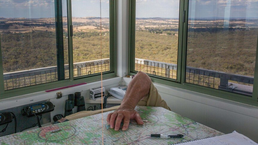 Only Paul Leishman's elbow is visible as he leans to retrieve something inside his cramped 1.9-square-metre fire lookout cabin.