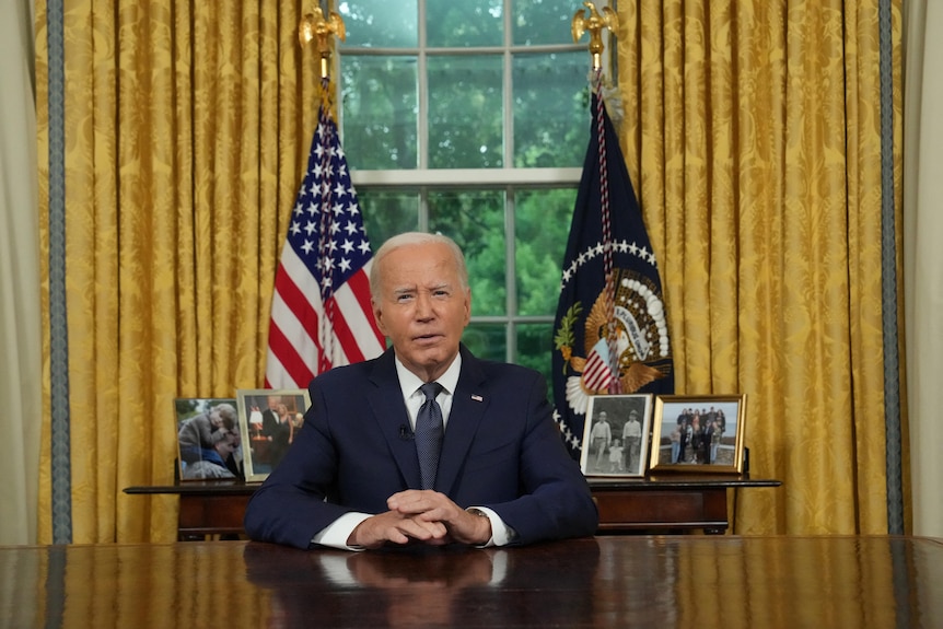 Joe Biden sitting at the resolute desk in the oval office 