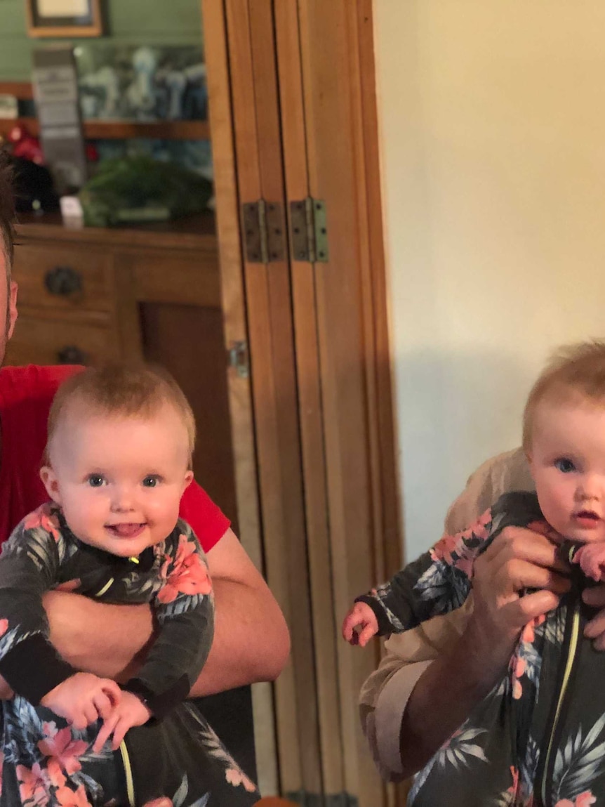 A grandfather holds his twin granddaughters.