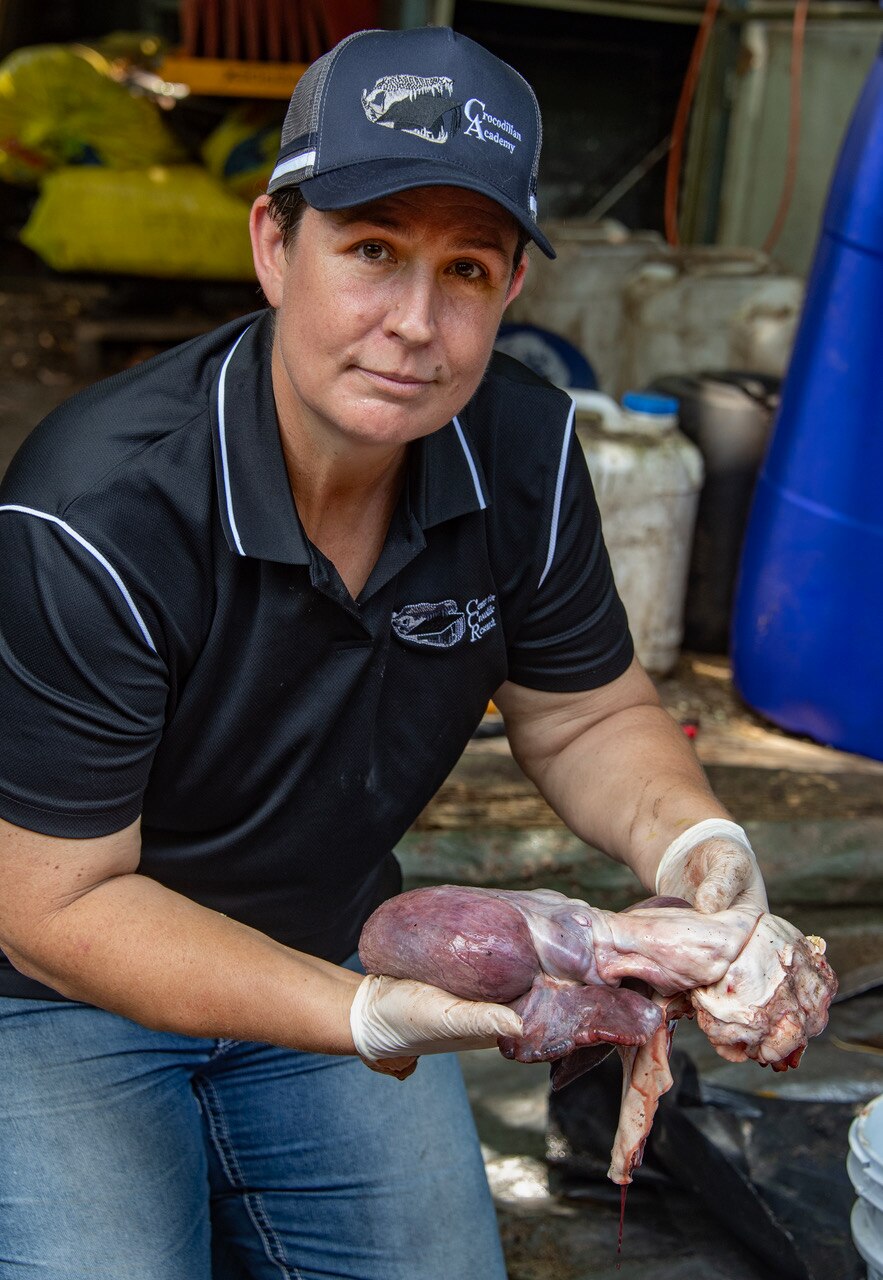 Mujer sosteniendo corazón animal con manos enguantadas