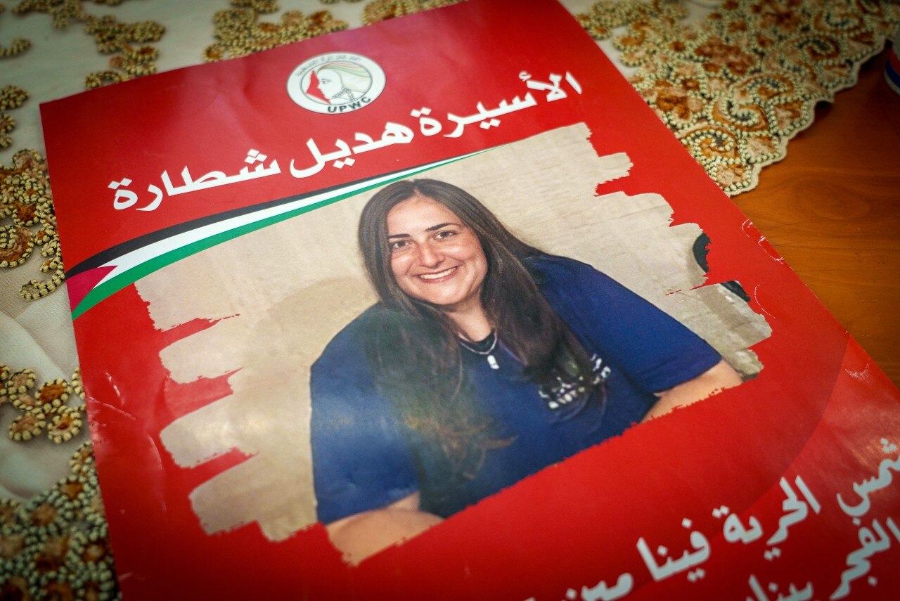 A poster with the picture of a smiling woman on it, with Arabic writing.