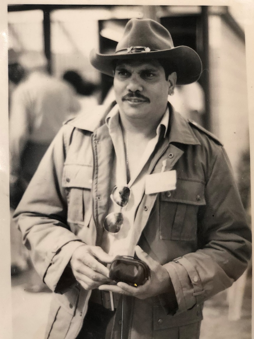 A young man holding a small bag.