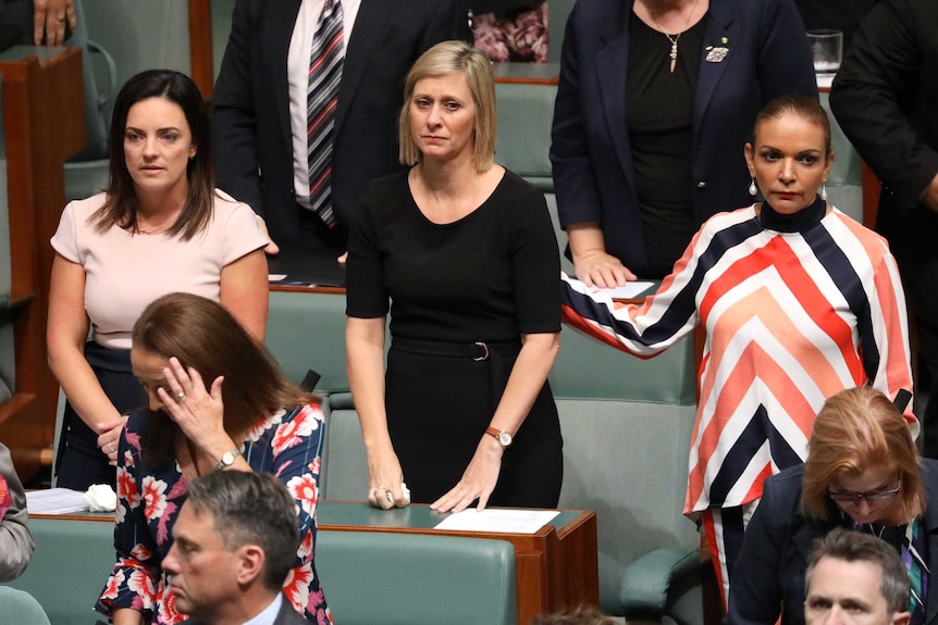 Anne Aly places her hand on Susan Lamb's back, as Emma Husar and other MPs stand in solidarity.