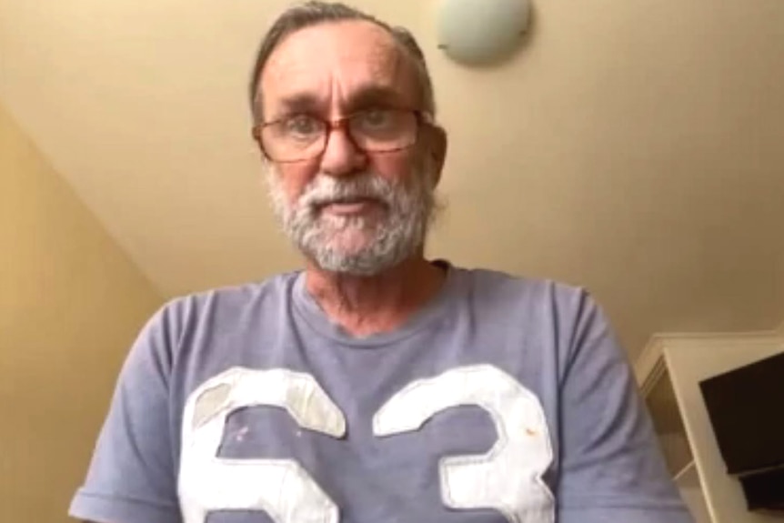 A man in a T-shirt and glasses speaking on a Zoom call