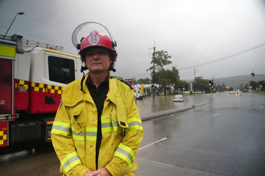 Firefighter looks at camera, truck in background