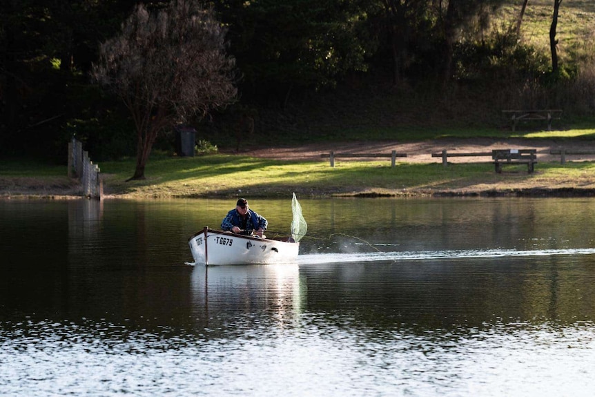 A fisherman in a boat on the Glenelg River in Nelson