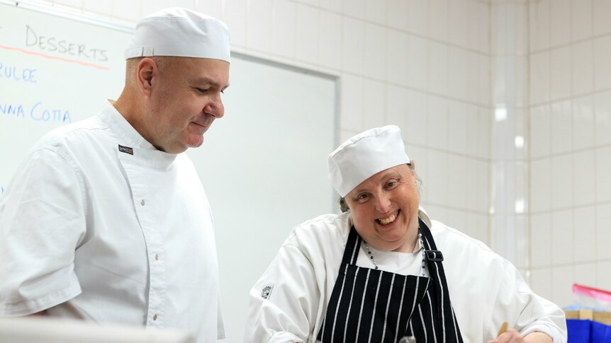 Sarah Elliot smiles as she works in the kitchen as she is watched by Stephen Hoger.