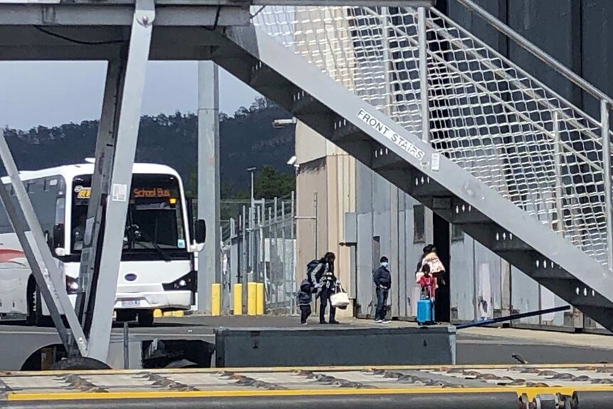 Travellers into Hobart from New Delhi on tarmac near a bus.