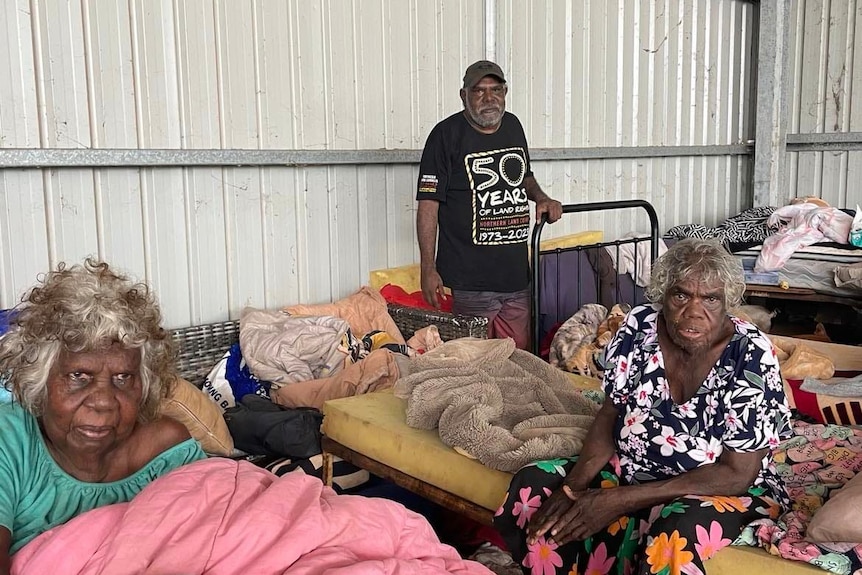 three aboriginal people inside a flood shelter surrounded by blankets