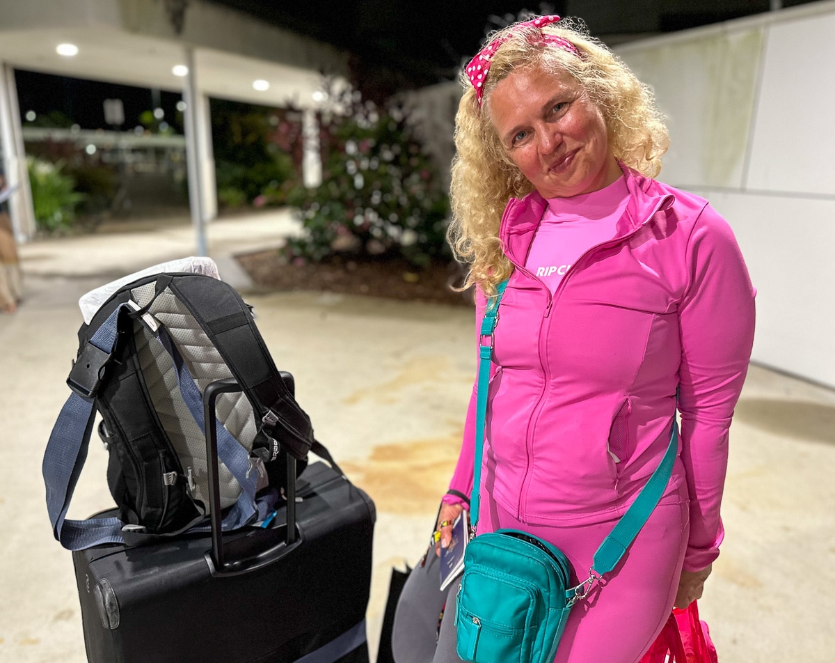 Uma mulher vestida de rosa com uma mochila ao lado. 