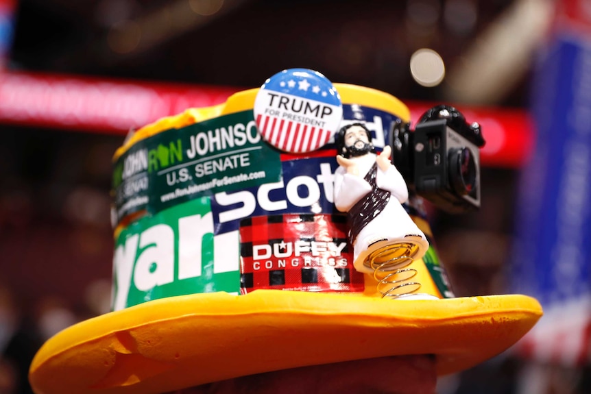 A delegate wears a "cheesehead" hat adorned with buttons and stickers - and a figure of Jesus.
