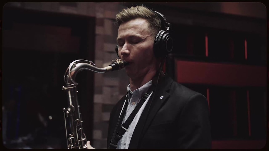 Saxophonist Azat Bayazitov with his tenor sax and headphones on, performing in a recording studio