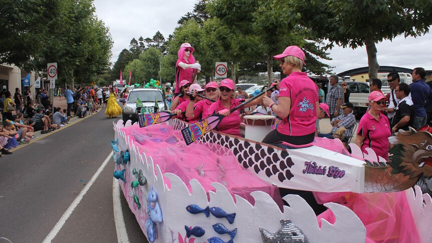 Women in pink pretending to row a boat down the street in Port Lincoln during the 2016 Tunarama festival.