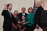 Brett Kavanaugh swearing an oath as his family and Trump watch on.