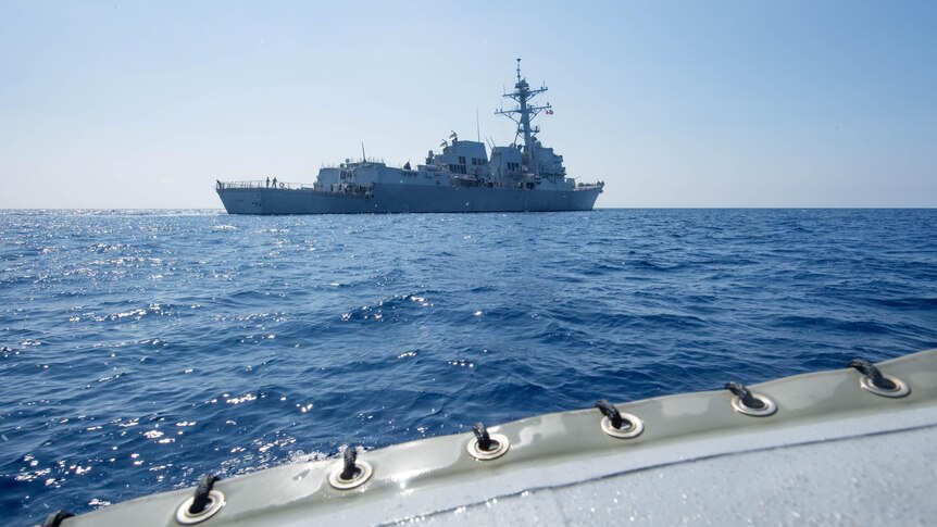 The American guided-missile destroyer USS Dewey is seen in the distance as it transits the South China Sea, May 2017.