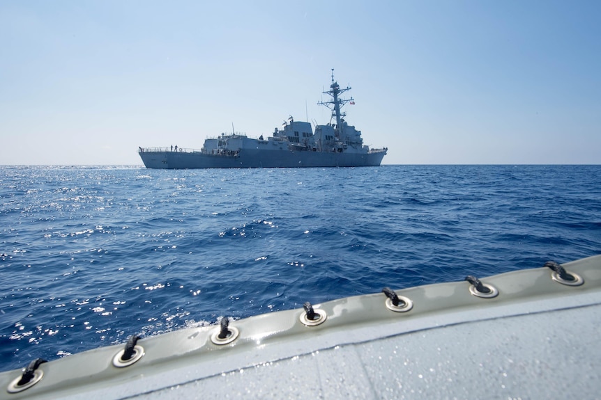 The American guided-missile destroyer USS Dewey is seen in the distance as it transits the South China Sea, May 2017.