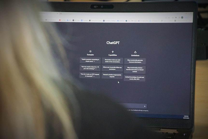 A woman sits in front of a computer open to a screen showing black and white text