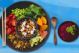 A birds-eye shot of a bright salad, with chickpeas and feta in the middle surrounded by colourful ingredients.